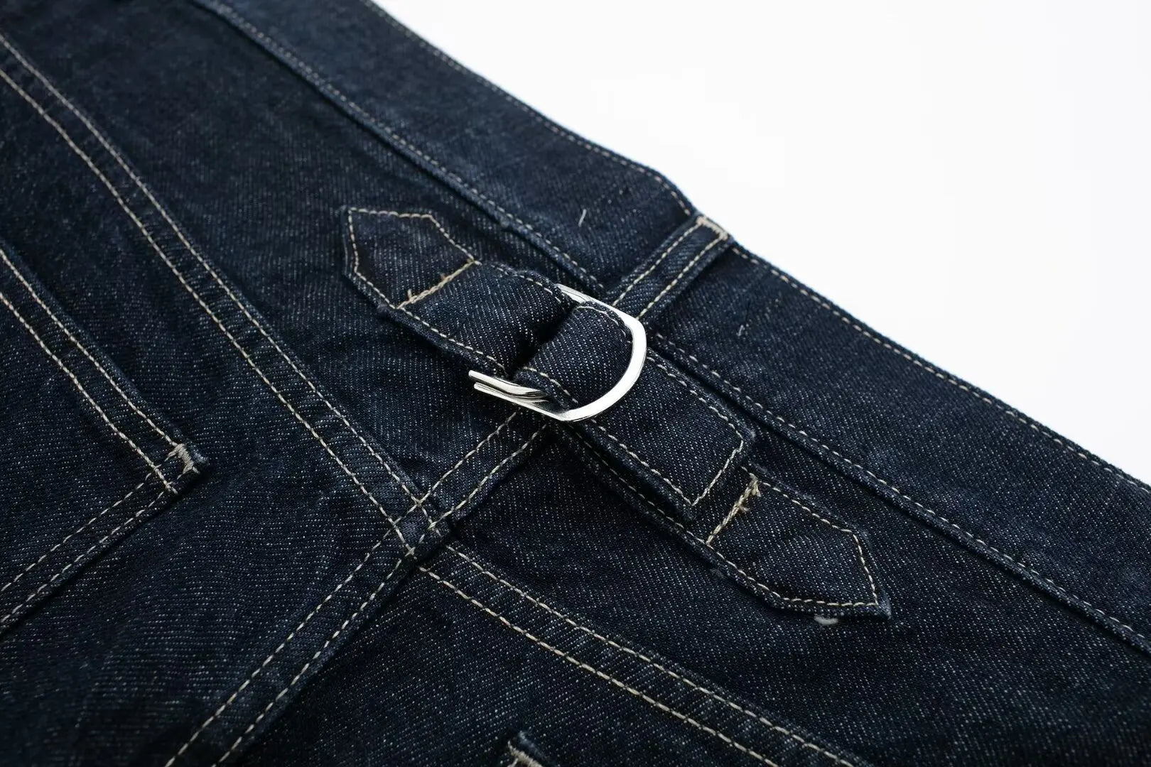 Close-up of a blue denim pocket with a metal button on a white background