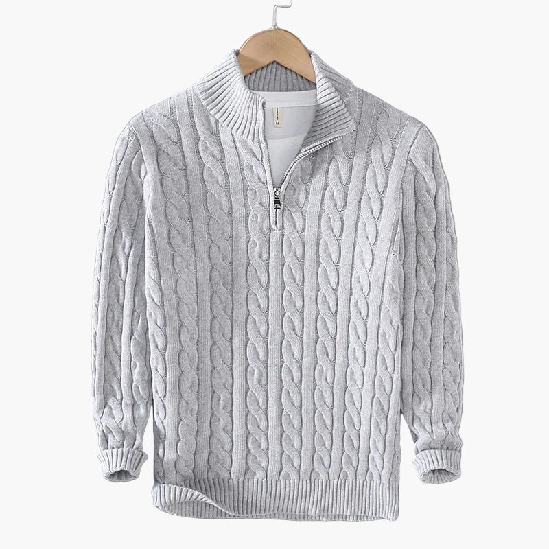 Gray cable knit sweater with a quarter zip on a hanger against a gray background
