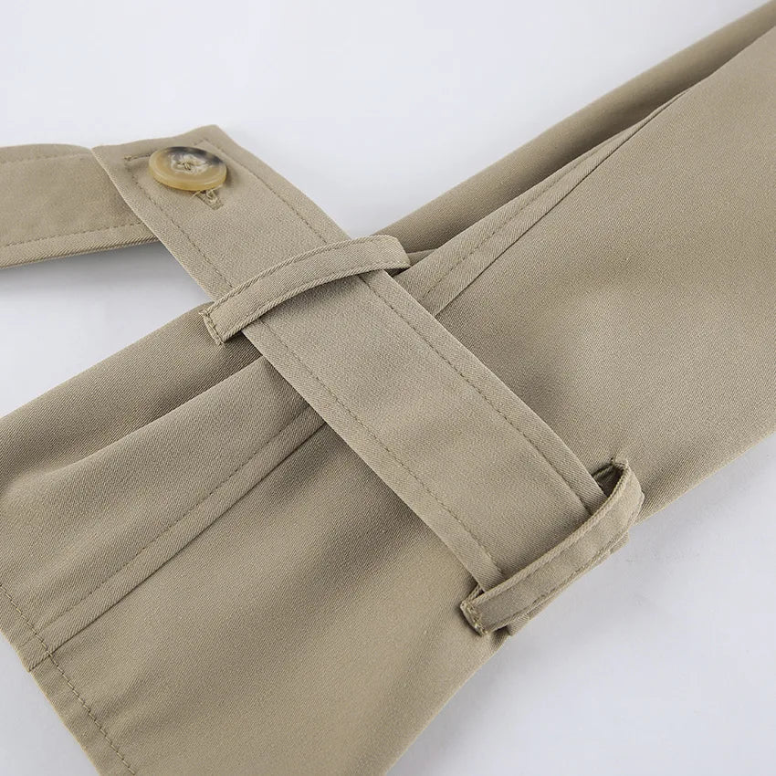 Close-up of beige pants with a belt and button on a white background