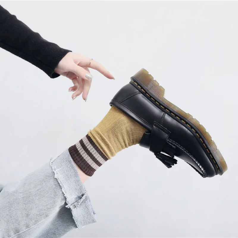 Wearing classic black leather loafers with gray tailored trousers.
