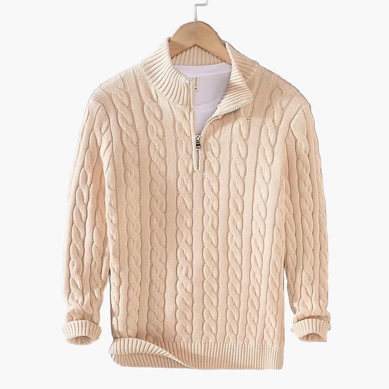 Beige cable knit sweater on a hanger against a gray background