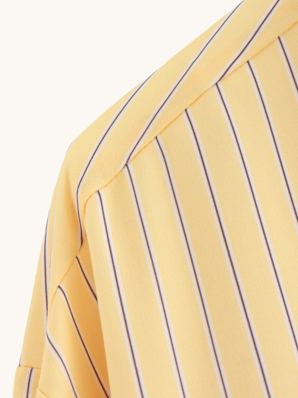 Close-up of a yellow shirt with purple vertical stripes on a light gray background