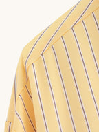 Close-up of a yellow shirt with purple vertical stripes on a light gray background