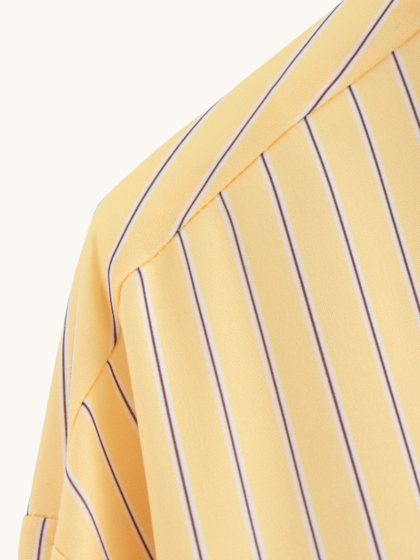 Close-up of a yellow shirt with purple vertical stripes on a light gray background