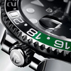 Close-up of a Rolex watch with green bezel and silver accents.
