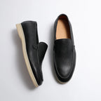 Pair of black leather loafers on a light gray background