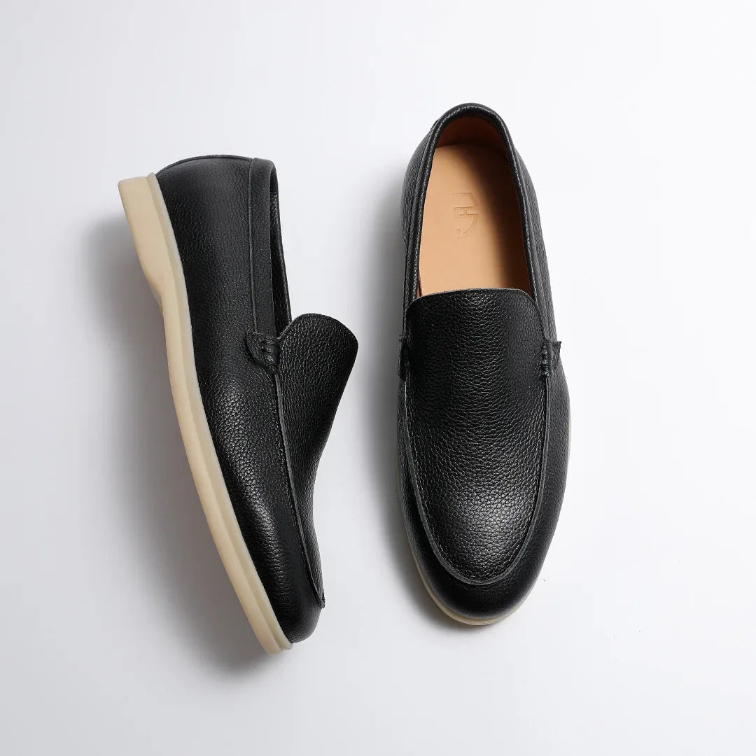 Pair of black leather loafers on a light gray background