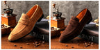 Pair of brown suede loafers on a wooden surface with coffee beans and a grinder.