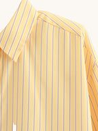 Yellow striped shirt on a hanger against a white background