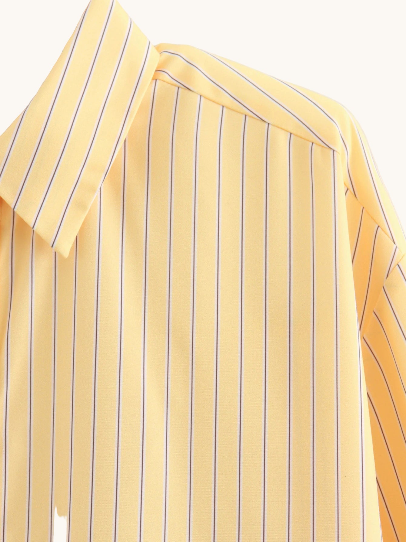 Yellow striped shirt on a hanger against a white background