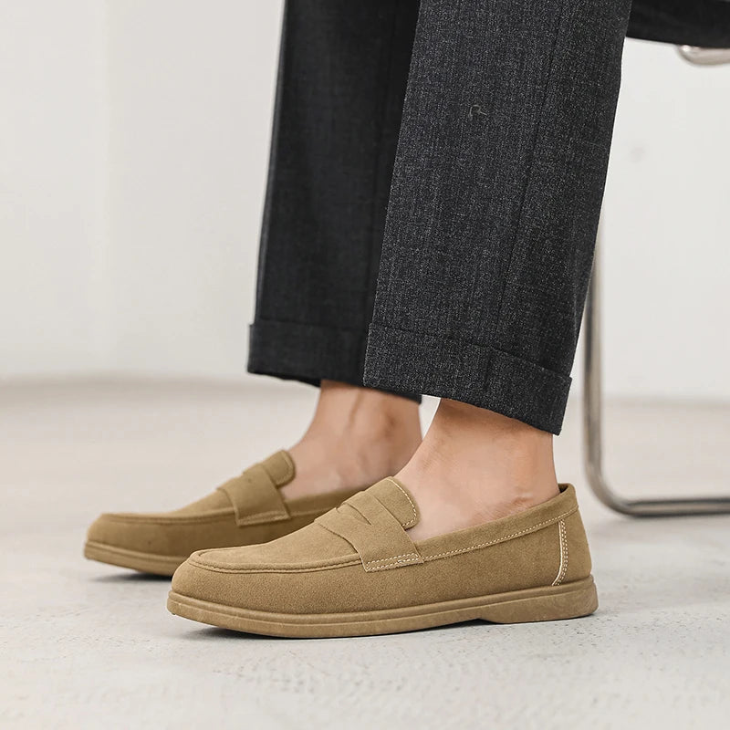 Tan loafers worn with dark pants on a light background