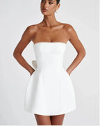 Woman wearing a white strapless dress with ruffled details on a plain background