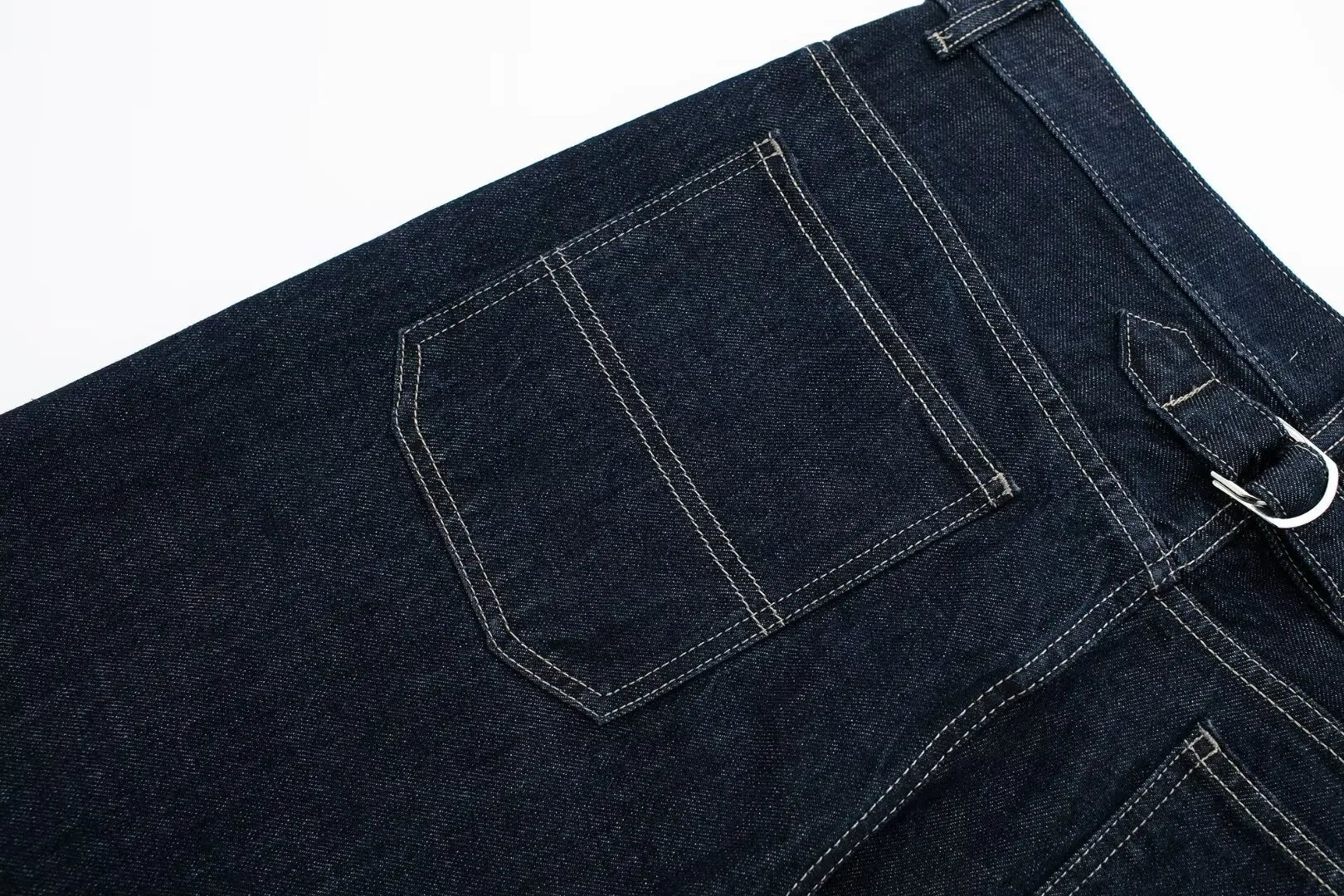 Close-up of dark blue denim jeans with a white background