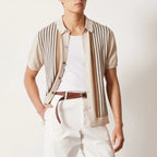 Person wearing a striped shirt over a white top with white pants on a light background