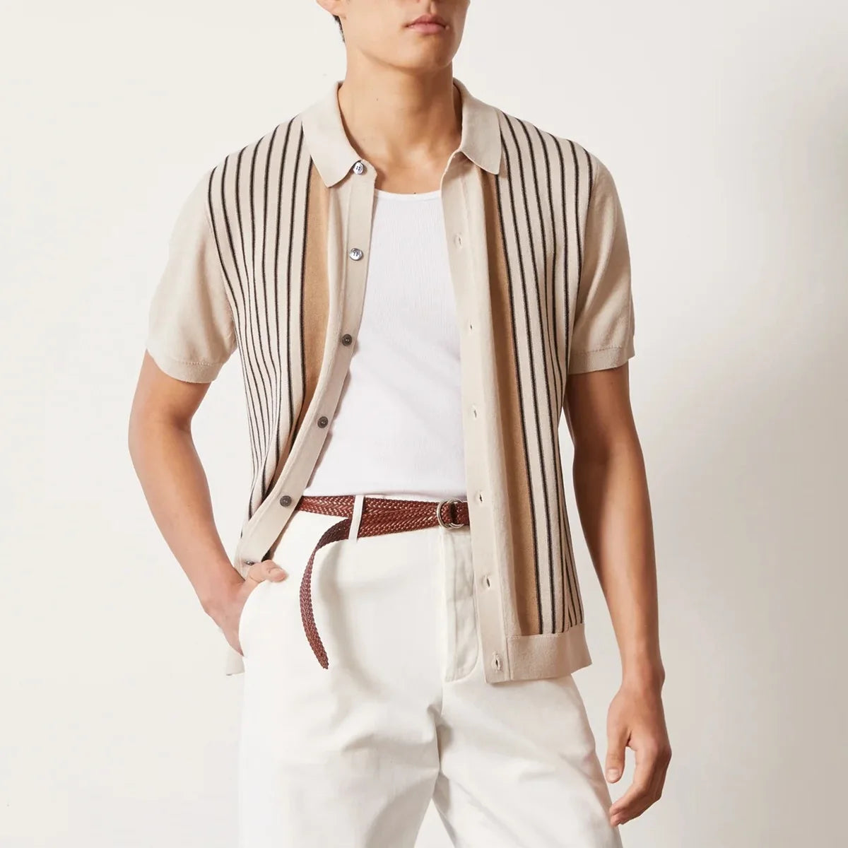 Person wearing a striped shirt over a white top with white pants on a light background