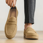 Beige loafers being held up with a neutral background