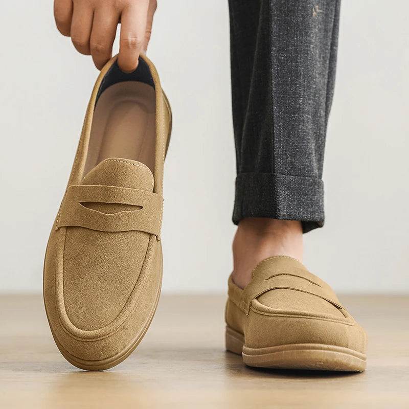 Beige loafers being held up with a neutral background