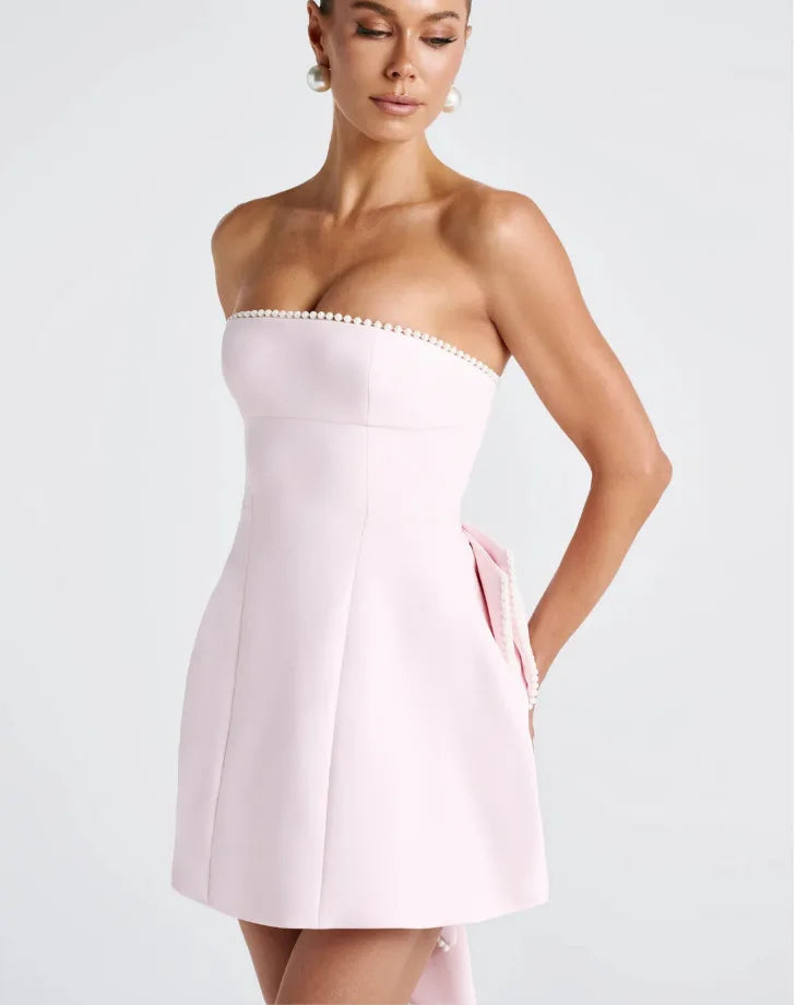 Woman wearing a strapless pink dress on a plain background