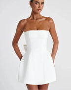 Woman wearing a strapless white dress with pearl details on a white background