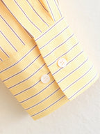 Close-up of a yellow shirt with blue stripes and buttons on a light background