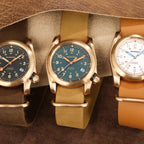 Three watches with gold and brown straps on a brown background