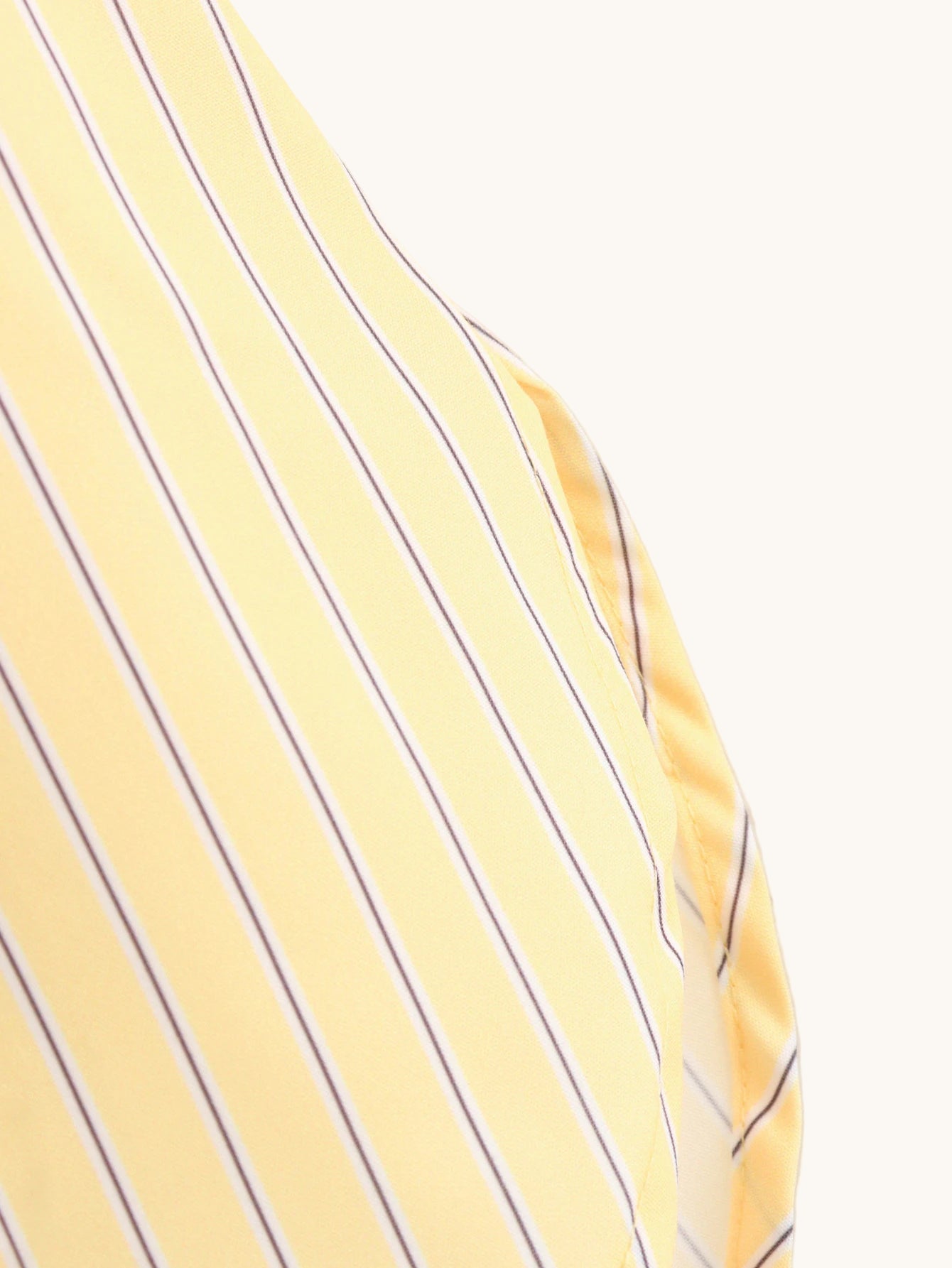 Close-up of a yellow shirt with blue stripes on a plain background