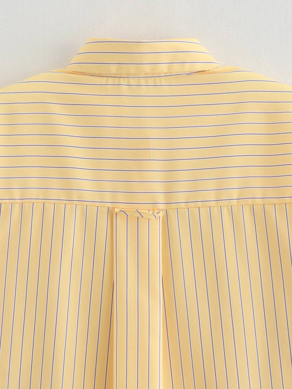 Close-up of a yellow striped shirt with a plain background
