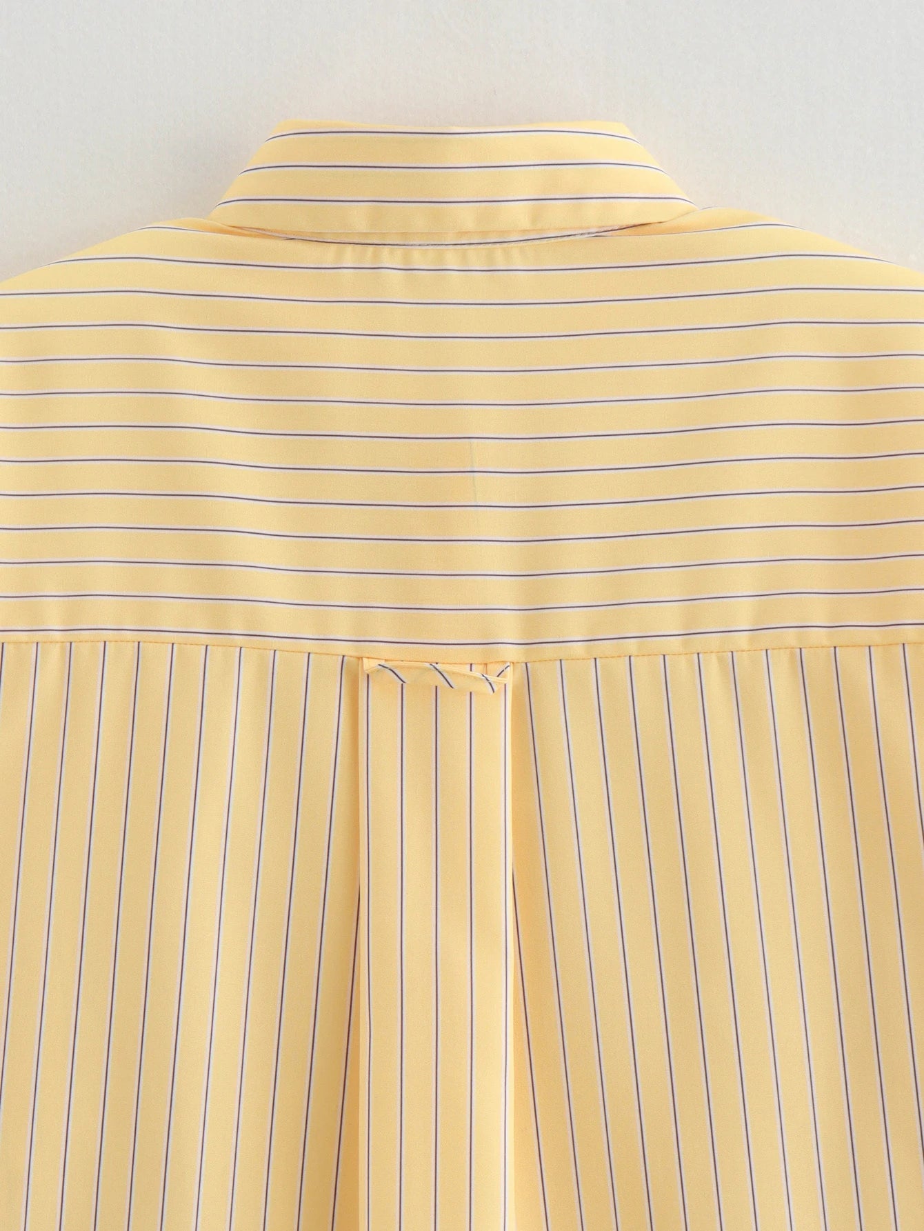 Close-up of a yellow striped shirt with a plain background