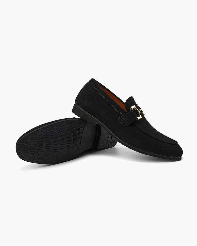 Black loafers with a gold buckle on a white background