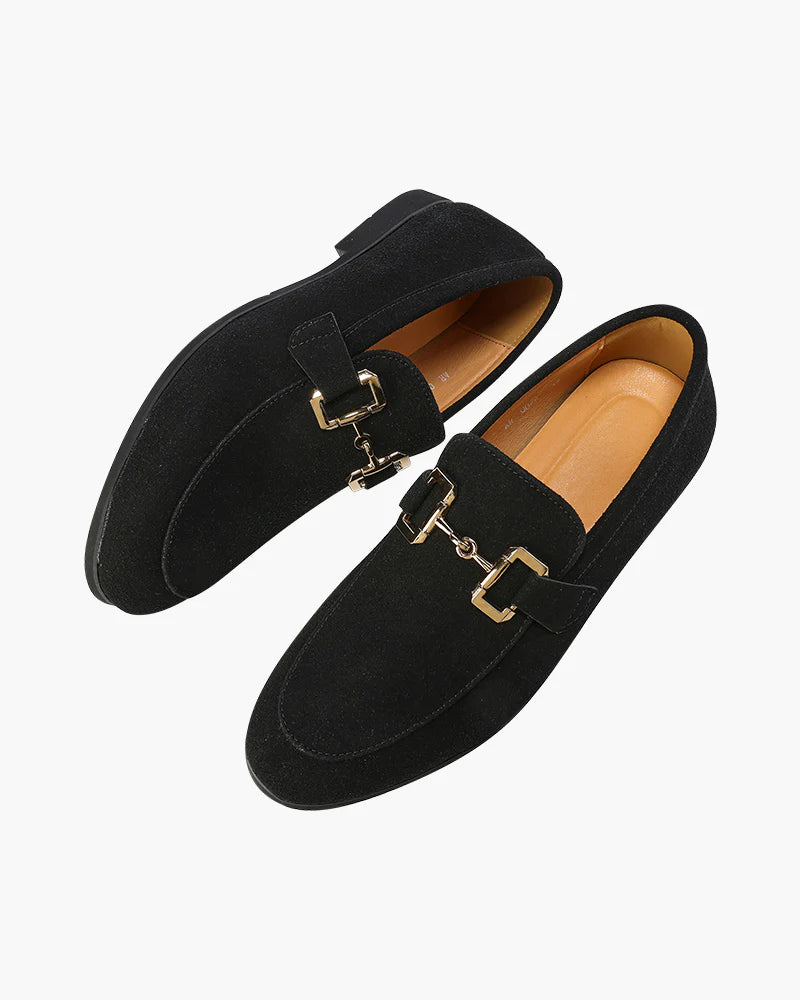 Pair of black loafers with gold buckles on a white background