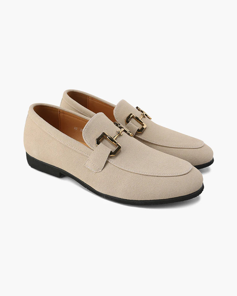 Pair of beige loafers with a gold buckle on a white background