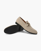 Beige loafers with a gold buckle on a white background