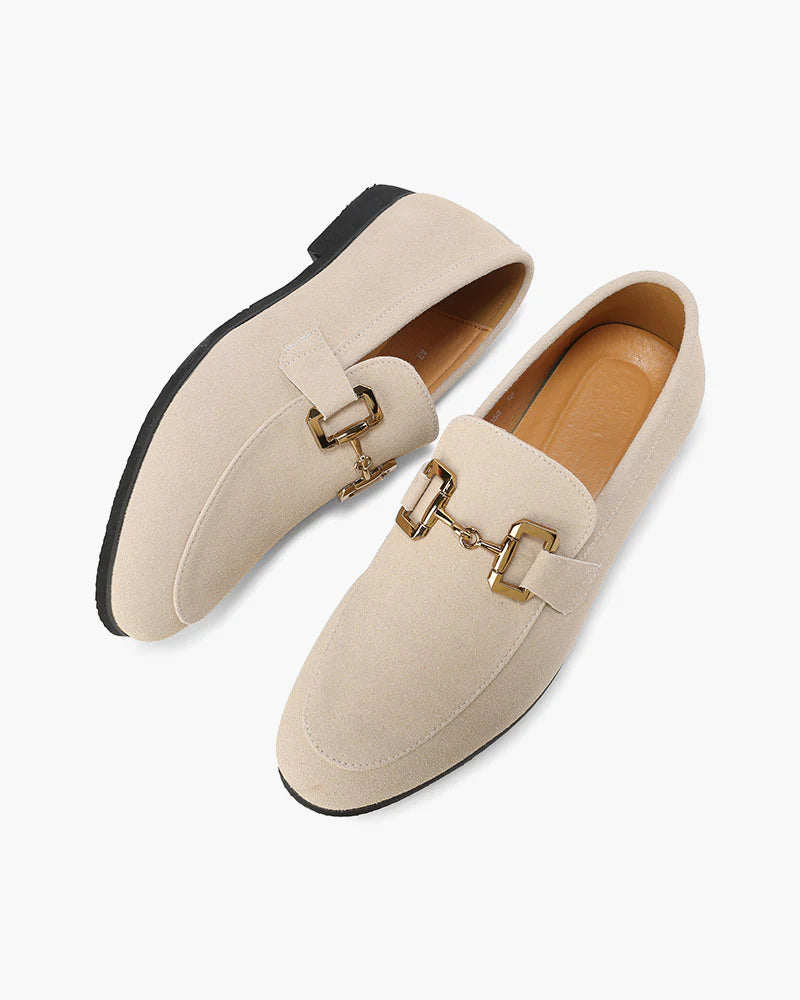 Pair of beige loafers with gold buckles on a white background
