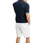 Person wearing a navy polo shirt and white shorts on a white background