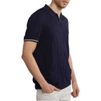 Man wearing a navy polo shirt with white trim on a white background