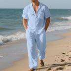 Man wearing a light blue outfit on a beach with ocean waves in the background