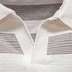 Close-up of a white garment with brown striped patterns on a neutral background