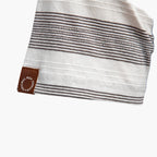 Close-up of a white towel with brown stripes and a brand logo on a white background