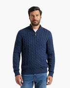 Man wearing a blue cable knit sweater on a white background