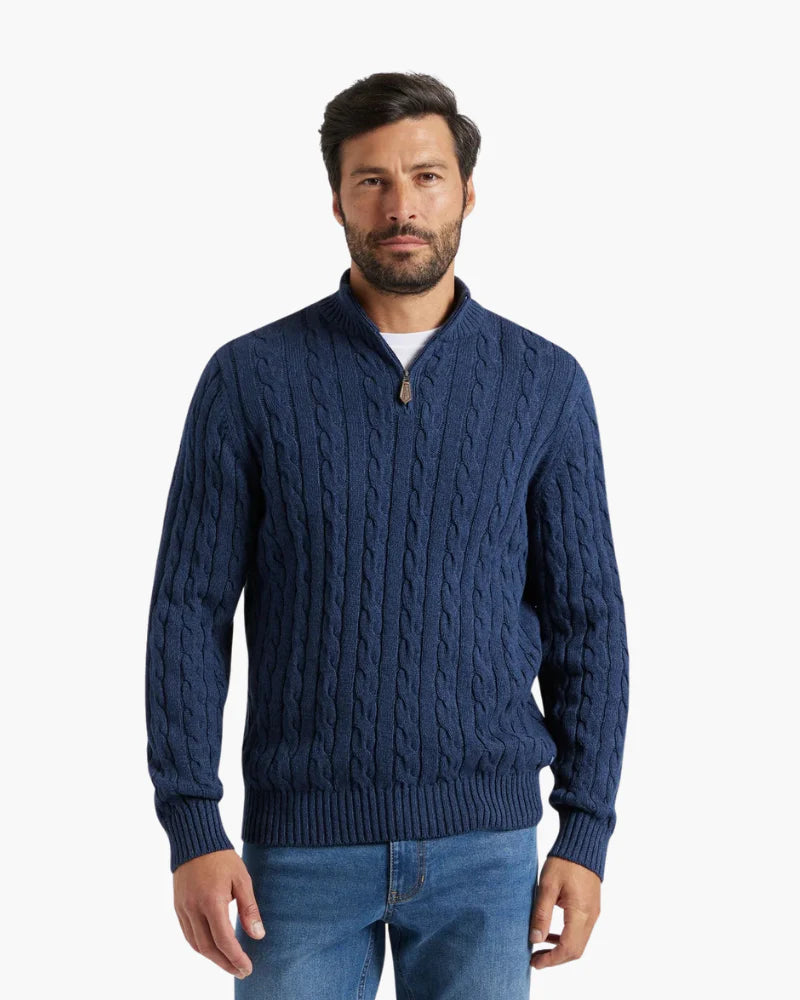 Man wearing a blue cable knit sweater on a white background