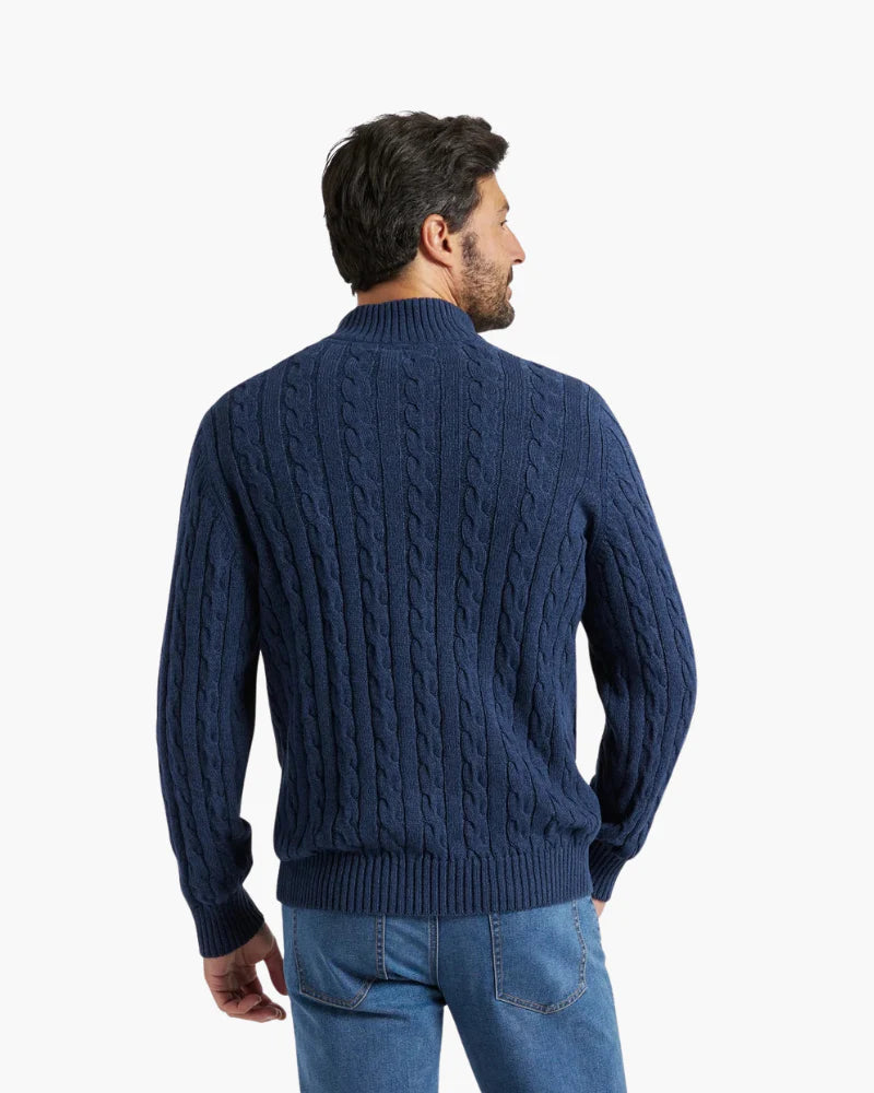 Man wearing a blue cable knit sweater on a white background