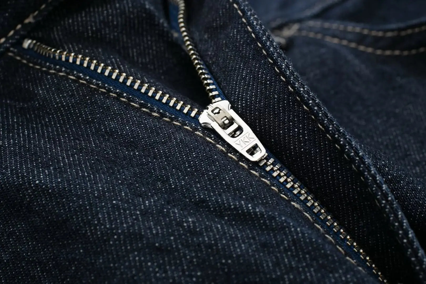 Close-up of a zipper on a dark blue denim fabric