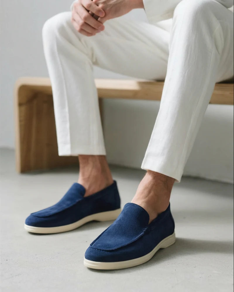 Person wearing blue loafers and white pants sitting on a wooden bench.