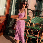 Woman in a pink floral dress standing in front of green and white checkered chairs.